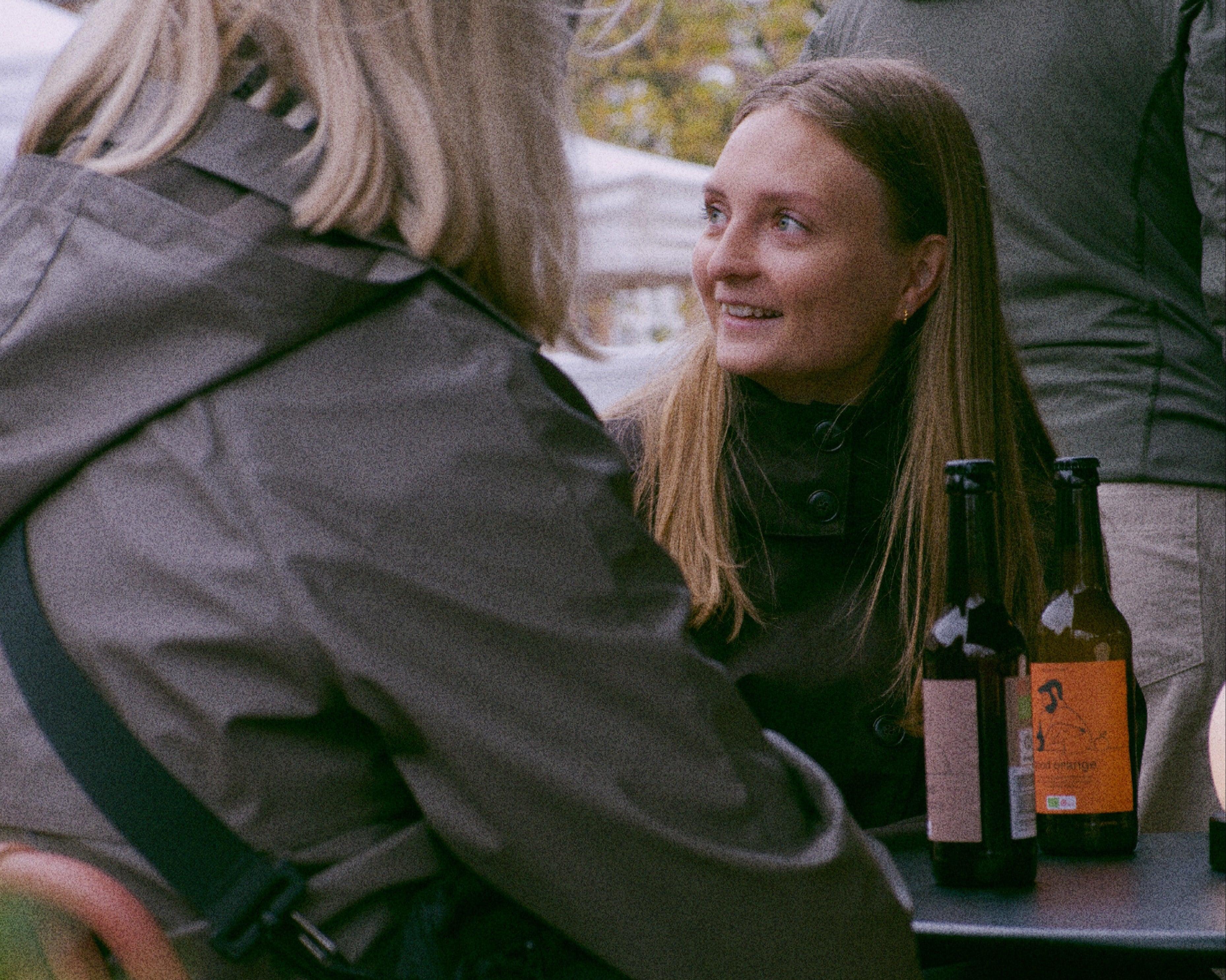 Two people sitting outdoors with bottles on a table