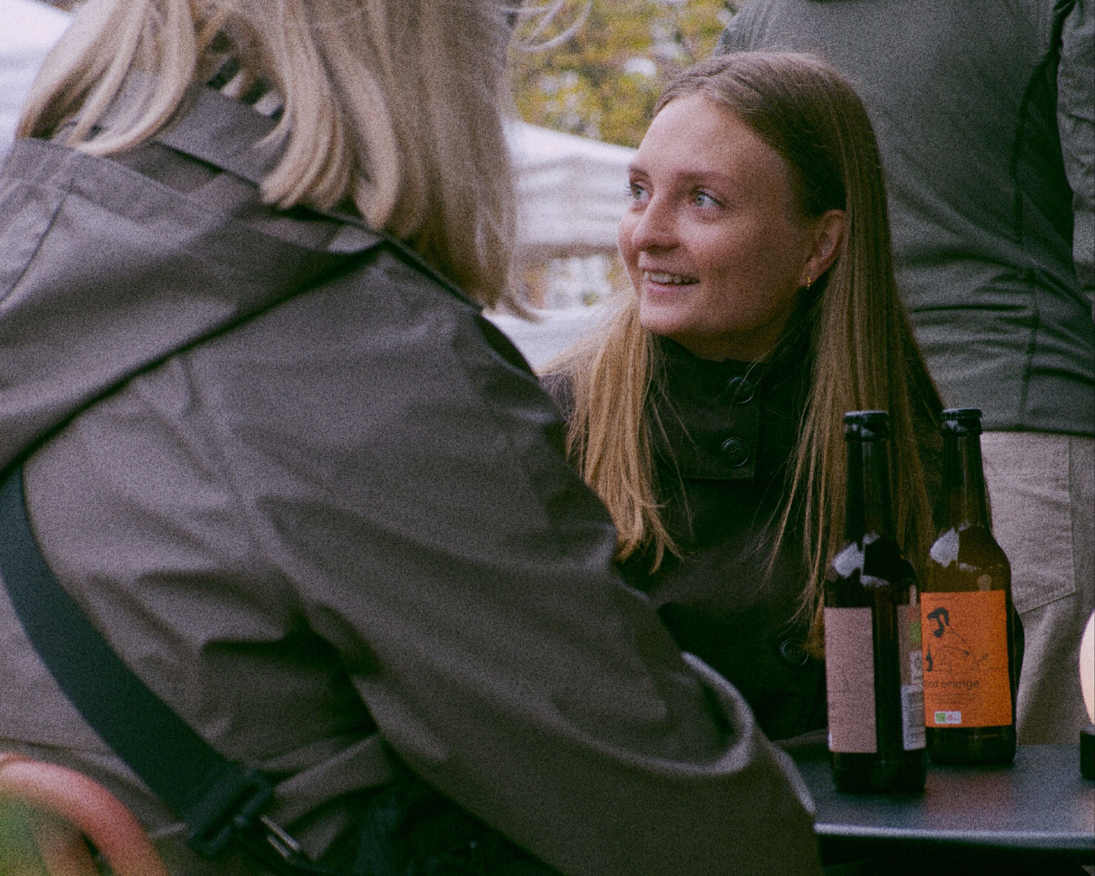 Two people sitting at a table with our organic and fermentet good soda bottles, engaged in conversation outdoors.